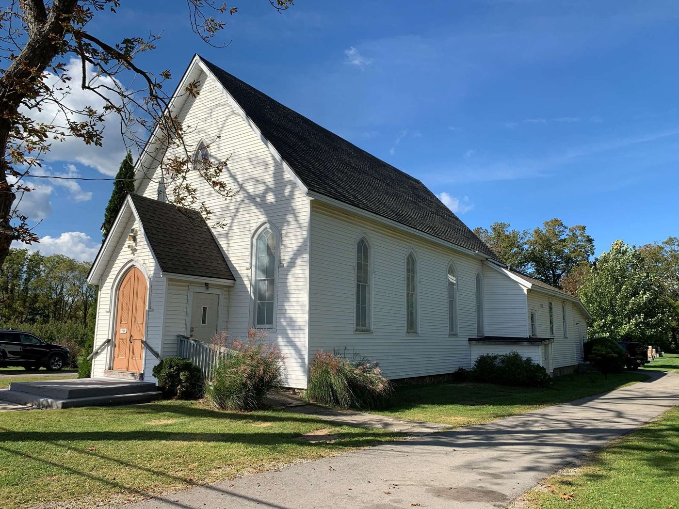 The white wooden church with its pointed-arch windows and new dark roof on a sunny day